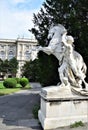 White marble statue of man holding a fiery horse in Vienna, in the center of the garden in the museum district.