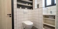 Contemporary bathroom corner with white toilet and shelving Royalty Free Stock Photo
