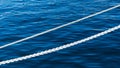 White marine mooring rope against background of blue water of Black Sea. Two white nautical cord. Background image Royalty Free Stock Photo