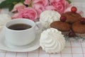 White marshmallows, chocolate muffins, a cup of coffee and roses.