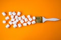 White marshmallows on yellow background with painting brush. Creative concept of unheathy junk food