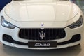 White Maserati Ghibli close up front side view brand logo trident display at showroom dealer at the Siam Paragon Mall in Bangkok,