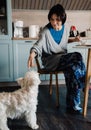 White mature woman playing with her dog while having breakfast Royalty Free Stock Photo