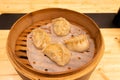 White meat, shrimps and mushroom steamed dumplings on a wooden table in a wooden steamer in an asian restaurant or chinese bar