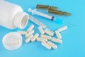 White medical containers, Pills, Syringe, ampoules for injections on a blue medical background. close up, top view