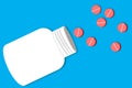 White medical drug bottle and red pills or tablets spilling out of it on blue background Royalty Free Stock Photo