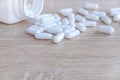 White medical pills spilling out of a drug bottle on a wooden backgrounds Royalty Free Stock Photo