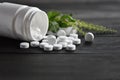 White medical pills and tablets spilling out of a drug bottle. top view with copy space. On Black wood Background. Natural herbs, Royalty Free Stock Photo