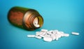 White medical tablets spilled out of a glass bottle isolated on blue background