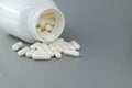 White medicine bottle spills pills over gray background Royalty Free Stock Photo