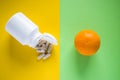 White medicine pills with pill bottle opposite of orange on yellow and green background