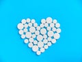 White medicine pills in the shape of a heart on a blue background top view with copy space. Royalty Free Stock Photo