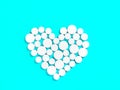 White medicine pills in the shape of a heart on a blue background top view with copy space. Royalty Free Stock Photo