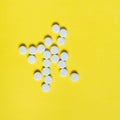 White medicine pills on yellow background. Medical and healthcare concept