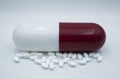 White medicine pils and a large white and red capsule.  on white background. Royalty Free Stock Photo