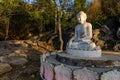White meditating Buddha statue sits on the rock pile among forest trees in the afternoon time at India. Great religious Royalty Free Stock Photo