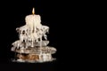 White melting candle standing on the rocks on a black background