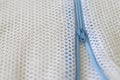 White mesh bag with blue zipper for washing machine.