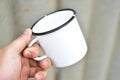 White metal enameled mug in the hands of a person Royalty Free Stock Photo