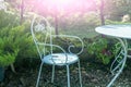 White metal iron chair and table outdoors. Retro styled furniture in magic green summer garden, symbols of Alice in Wonderland Royalty Free Stock Photo