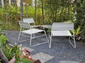 White metal outdoor furnitire in the tropocal garden surround with plants on the gravel floor