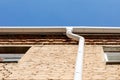 White metal pipe from the drain on the wall of a brick building. Water drainage from the roof. Drain on the roof of the Royalty Free Stock Photo