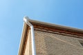 White metal pipe from the drain on the wall of a brick building. Drain on the roof of the house. Roof drainage. Water Royalty Free Stock Photo