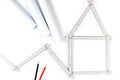 White meter tool forming a house, two drawing pencils and paper