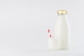 White milk, dairy product in glass bottle  mock up with glass, red straped straw in soft light white background. Royalty Free Stock Photo