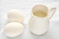 White milk jug with milk and two eggs on a wooden table Royalty Free Stock Photo