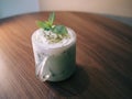 White milky drink with the greens on itin a glass cup on the table