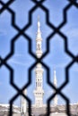 White minaret of the Prophet\'s Mosque through the bars in the city of Medina