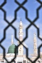 White minaret of the Prophet\'s Mosque through the bars in the city of Medina