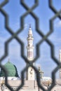 White minaret of the Prophet\'s Mosque through the bars in the city of Medina