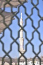 White minaret of the Prophet\'s Mosque through the bars in the city of Medina