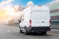 White mini bus is moving motion blur along city highway bypass road with beautiful sky before sunset. Fast express delivery