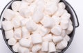 White mini puffy marshmallows ia a black bowl on white background with copy spase. Top view, close-up. Royalty Free Stock Photo