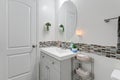 White Minimal Bathroom Interior with Multi Colored Accent Tiles and Small Sink Vanity with Oval Mirror