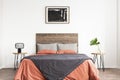 White minimal bedroom with wooden headboard and coral and grey bedsheets