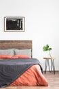 White minimal interior with simple bed, coral and grey linen bedsheets and nightstand