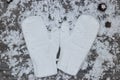 white mittens on the background of snow-covered wood surfaces wi