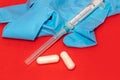 White 2 ml syringe macro on red, blue glove, pills Royalty Free Stock Photo