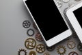 White mobile phone with black screen and small gears on gray table Royalty Free Stock Photo