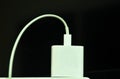 White mobile phone charger stabbing in plug in socket on black background Royalty Free Stock Photo