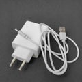 White mobile phone charging adapter with white USB type cable on black surface Royalty Free Stock Photo