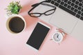 White mobile phone with clipping path on touchscreen, hot cup of coffee, black eye glasses on notebook`s keyboard, analog clock Royalty Free Stock Photo