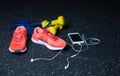 A white mobile phone with headphones, pink sneakers, two yellow dumbbells and expander on a blurred background. Royalty Free Stock Photo
