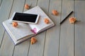 White mobile phone, pen, notebook and vintage roses on a blue grey background Royalty Free Stock Photo