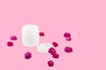 White mocap jar for cream, balm, lotion and a small pink-Red roses on a pink background. Isolated Royalty Free Stock Photo