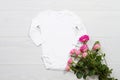 White mockup newborn shirt. Wooden background, pink roses, happy birthday. Blank template jumpsuit bodysuit front top view. Baby Royalty Free Stock Photo